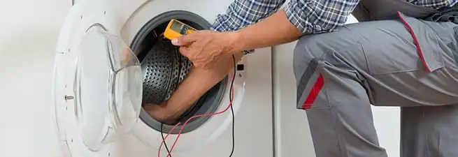 Dryer repair technician inspecting and repairing a clothes dryer in Baton Rouge, LA