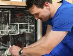 Dishwasher repair technician inspecting and servicing an open dishwasher in Baton Rouge, LA