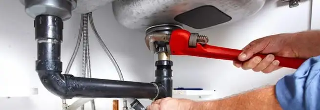 Garbage disposal repair technician tightening the sink drain and disposal connection in Baton Rouge, LA