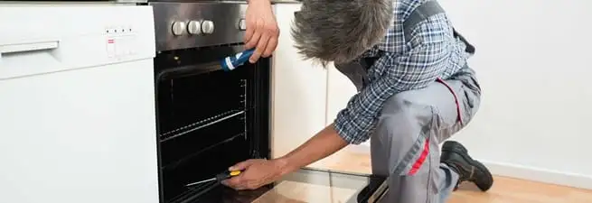 Oven repair technician inspecting and servicing an electric oven in Baton Rouge, LA