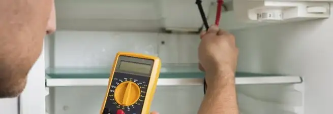 Refrigerator repair technician testing electrical components with a multimeter in Baton Rouge, LA