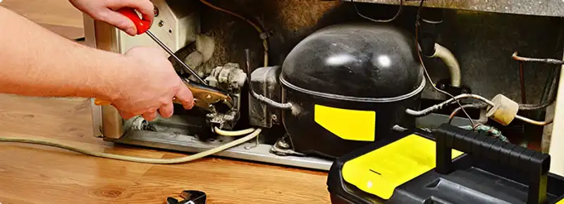 Refrigerator repair technician fixing the compressor and wiring in Baton Rouge, LA