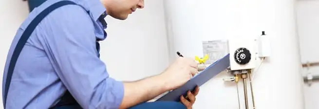 Water heater repair technician inspecting the unit and recording service notes in Baton Rouge, LA