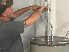 Water heater repair technician tightening supply line connections in Baton Rouge, LA