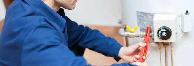 Water heater repair technician adjusting the temperature control and gas valve in Baton Rouge, LA